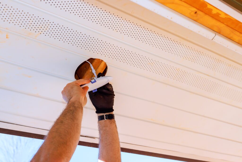 residential electrician applies lighting fixture in ceiling