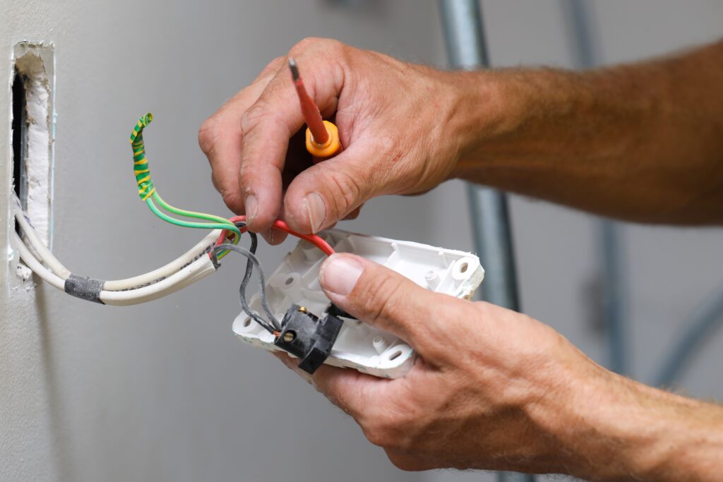 A close up of an electrician working on a light switch at a clients home.